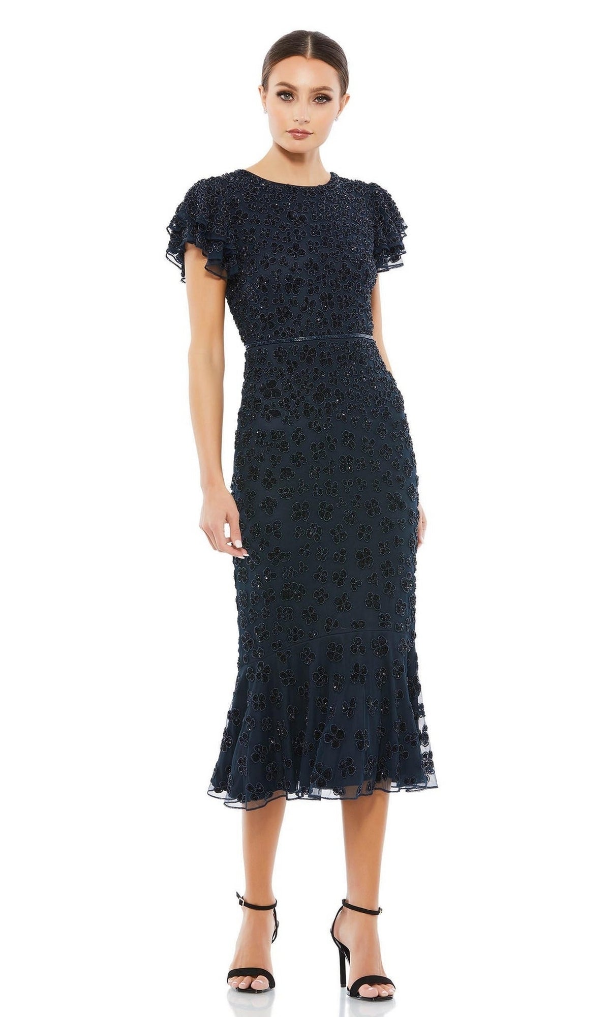 Woman wearing the Short Wedding Guest Dress 10771 by Mac Duggal, a navy blue semi-formal dress with ruffled sleeves and floral bead embellishments, paired with black heels, against a white background.